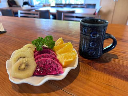 a plate of fruit on a table next to a cup at Arimabaru Beach Resort in Motobu
