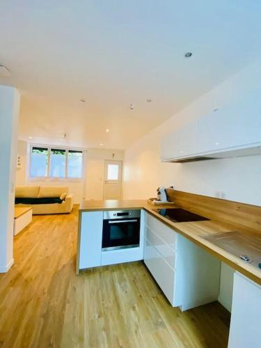 une cuisine avec des armoires blanches et un salon dans l'établissement Maison à Cholet, à Cholet