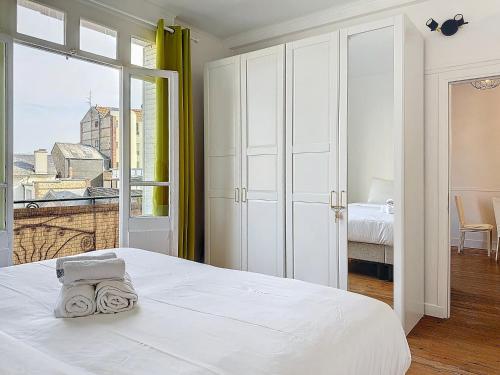 a white bedroom with a bed and a large window at Urban Haven in Deauville