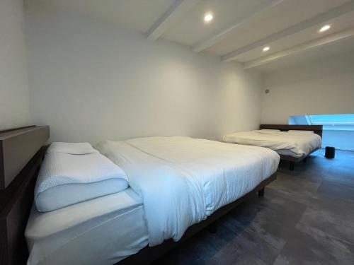 two beds in a room with white sheets at New三軒茶屋ハウス 渋谷まで電車5分 三軒茶屋駅徒歩6分 2023年フルリノベ戸建 in Tokyo
