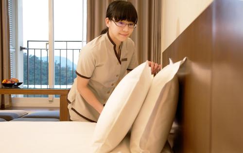 a woman standing next to a bed with pillows at RSL Cold & Hot Springs Resort Suao in Suao