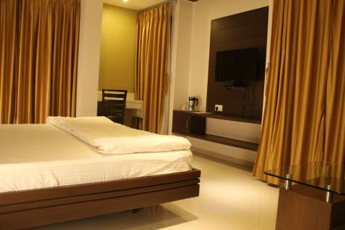a hotel room with a bed and a television at Hotel Marigold in Vadodara