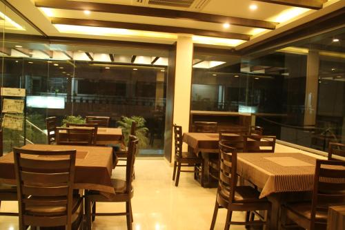 a dining room with tables and chairs in a restaurant at Hotel Marigold in Vadodara