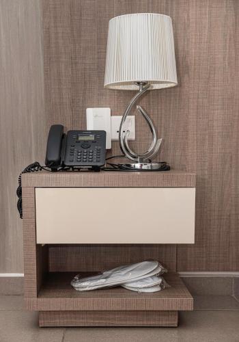 a desk with a phone and a lamp on it at Rise Urban Art Hotel in Larnaka