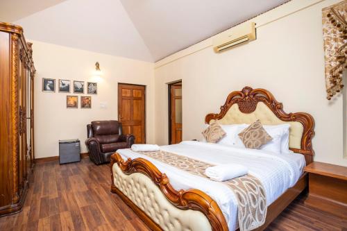 a bedroom with a large bed and a chair at Stone Wood Riverfront Resort, Siolim in Siolim