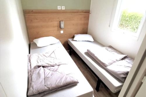deux lits dans une petite pièce avec une fenêtre dans l'établissement Biscarrosse MOBIL HOME Privilège XXL 6P Climatisé 40 m2, à Biscarrosse