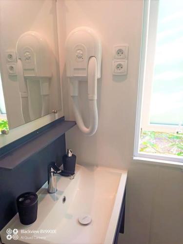 La salle de bains est pourvue d'un lavabo et d'un téléphone mural. dans l'établissement Biscarrosse MOBIL HOME Privilège XXL 6P Climatisé 40 m2, à Biscarrosse