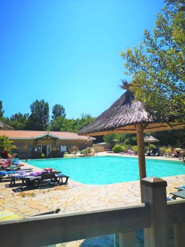 - une piscine avec des chaises et un parasol dans l'établissement Biscarrosse MOBIL HOME Privilège XXL 6P Climatisé 40 m2, à Biscarrosse