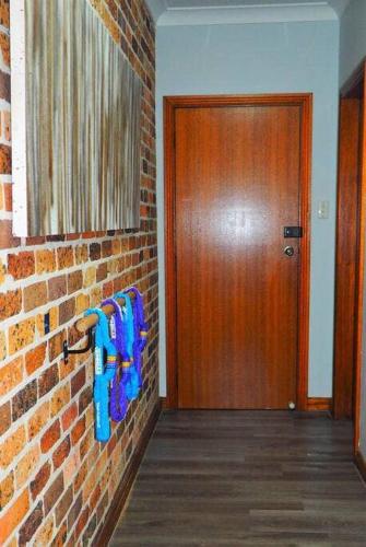 a hallway with a brick wall and a wooden door at Cozy Double Room - Mins to Station & Olympic Park - Shared Bathroom in Regents Park