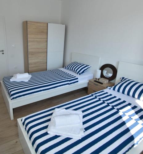 two beds in a room with blue and white stripes at POOl HOUSE BRUNO in Nin