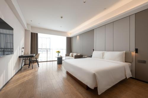 a bedroom with a large white bed and a desk at Atour Hotel Guangzhou Yueqiao Branch in Guangzhou