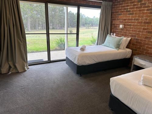 two beds in a room with a brick wall at Woolshed Hill Estate in Pokolbin