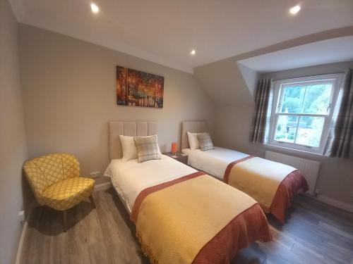 a bedroom with two beds and a chair and a window at Idyllic Waterside Penthouse in Callander