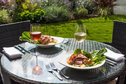 a table with two plates of food and two glasses of wine at The Park Hotel in Barnstaple