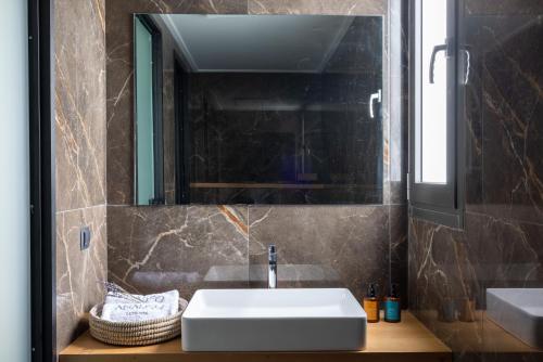 a bathroom with a white sink and a mirror at Anadeo Villas & Suites in Exanthia