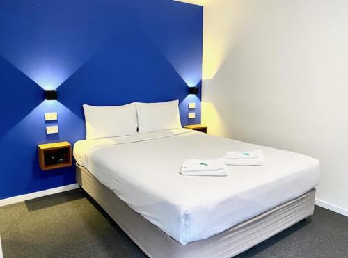 a bedroom with a large white bed with a blue wall at Huskisson Beach Escape in Huskisson
