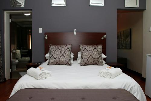 a bedroom with a large bed with towels on it at Aalwyns Guesthouse in Vanderbijlpark