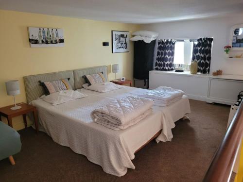 une chambre avec un lit avec des draps blancs et des oreillers dans l'établissement Appartement vue latérale mer, au Croisic