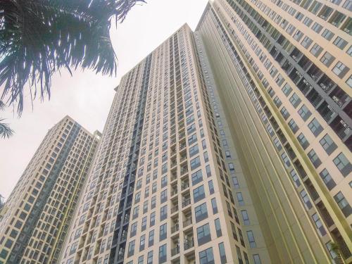 Dos edificios altos frente a una palmera en Nice and Elegant 2BR at Transpark Cibubur Apartment By Travelio, en Depok