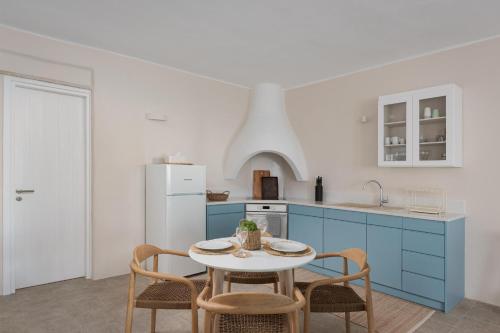 a kitchen with blue cabinets and a table and chairs at Morfes Luxury Apartments in Triandáros