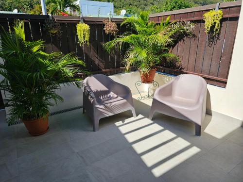 two chairs and a table on a balcony with plants at Cozy House in a private complex in Paea