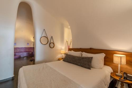 a bedroom with a white bed and an archway at Aroma Suites in Fira