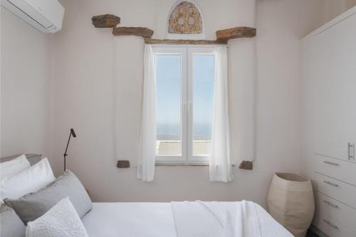 a bedroom with a bed and a large window at Morfes Luxury Apartments in Triandáros
