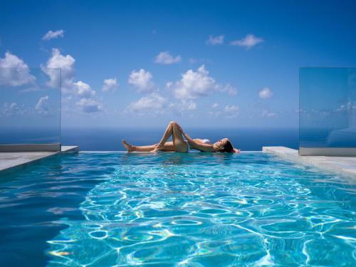 a woman laying on the edge of a swimming pool at Anadeo Villas & Suites in Exanthia