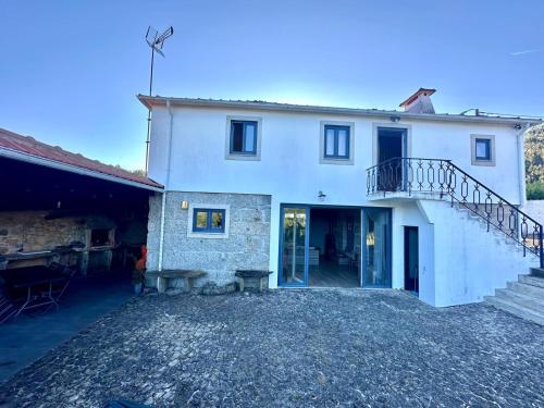 a large white house with a staircase in front of it at Casa da Ribeira - Arouca in Lázaro