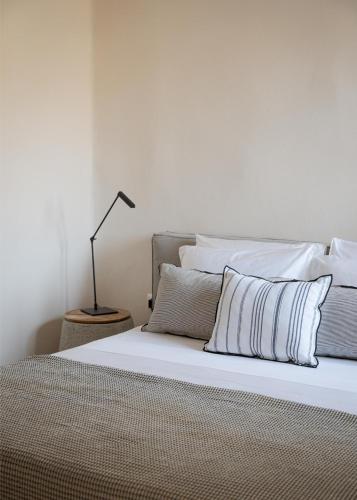 a bed with white sheets and a lamp on a table at Morfes Luxury Apartments in Triandáros