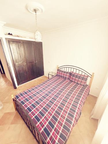 a bedroom with a bed with a plaid blanket on it at Résidence Tarifa in Mrarech