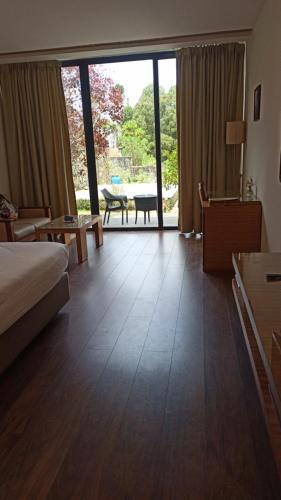 a hotel room with a bed and a large sliding glass door at Mountain Retreat Kodai in Kodaikānāl