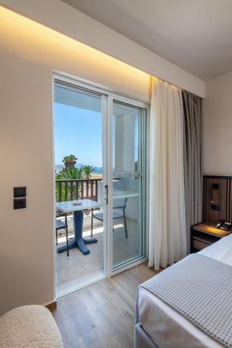 a hotel room with a bed and a balcony with a table at Kalimera Mare in Kardamaina