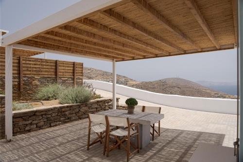 a patio with a table and chairs under a pergola at Morfes Luxury Apartments in Triandáros