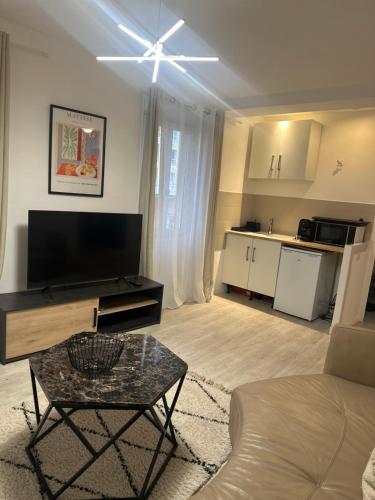 un salon avec une télévision à écran plat et une table dans l'établissement Carras, à Nice