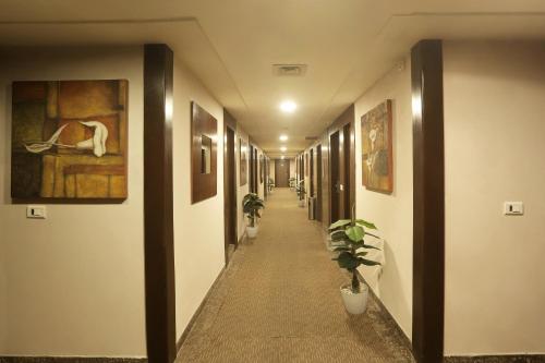 a hallway with paintings and plants on the walls at Vesta Maurya Palace in Jaipur