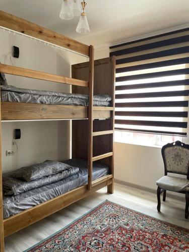 a bedroom with two bunk beds and a chair at Irbis Hostel in Karakol