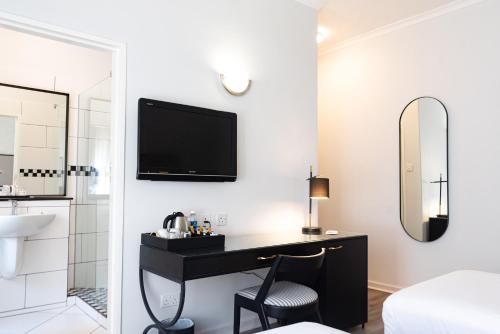 Un dormitorio con un escritorio y un televisor en la pared. en Cresta Churchill Hotel, en Bulawayo