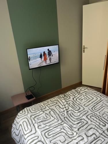 une chambre avec un lit avec une télévision à écran plat au mur dans l'établissement T2 Berck-plage, à Berck-sur-Mer