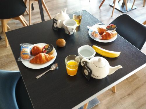 a black table with a breakfast of croissants and orange juice at Brit Hotel L'Arrivée Guingamp in Guingamp