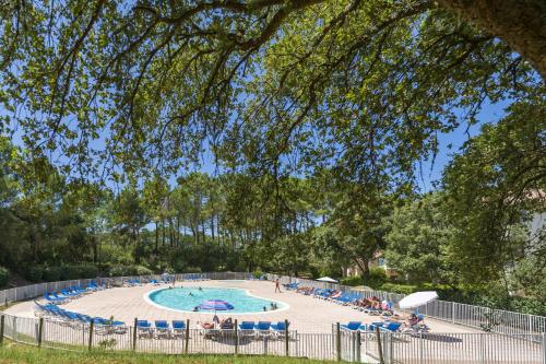 une piscine avec des chaises et des personnes assises autour de celle-ci dans l'établissement Domaine de Pinsolle, à Soustons