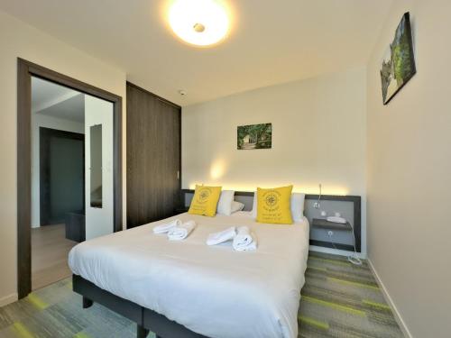 a bedroom with a large white bed with yellow pillows at Logis Le Prieuré in Locronan