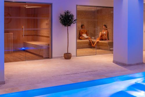 a bathroom with a pool and two people sitting in a shower at Garrigae Domaine de l'Esterel - piscine & SPA Cinq Mondes in Saint-Raphaël