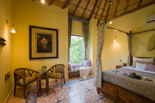 a bedroom with a bed and a table and chairs at Elivaas 5 BHK with Pool, Tents & Pond - Kaimalgarh Farmstay in Bhundsi