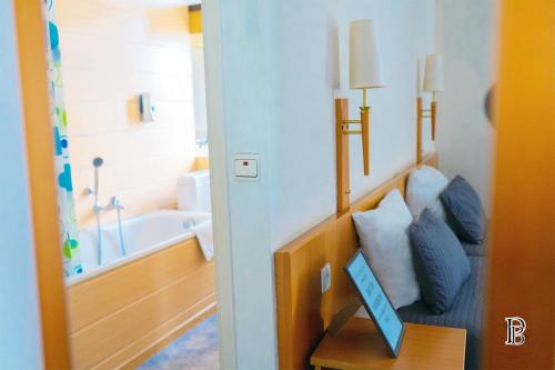 a room with a bathroom with a tub and a table at Hotel Professor Leuven Centrum in Leuven