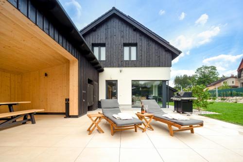 a patio with chairs and tables and a building at Residence Smržovka - Luxury House with Swimming Pool, Jacuzzi, Garden and BBQ in Jablonec nad Nisou