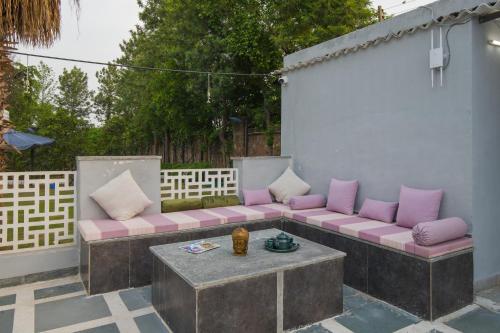 a couch with pillows sitting on a patio at Elivaas 5 BHK with Pool, Tents & Pond - Kaimalgarh Farmstay in Bhundsi