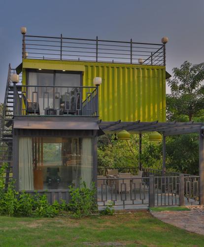 a large yellow building with a balcony on top at Elivaas 5 BHK with Pool, Tents & Pond - Kaimalgarh Farmstay in Bhundsi