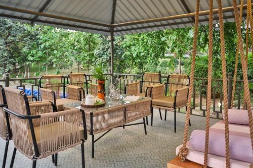 a patio with chairs and a table and a swing at Elivaas 5 BHK with Pool, Tents & Pond - Kaimalgarh Farmstay in Bhundsi