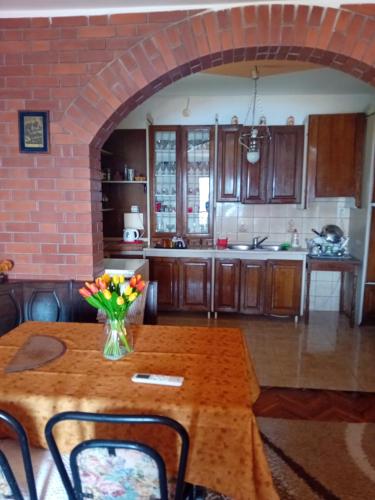 a kitchen with a wooden table with a vase of flowers on it at Guest House Cinderella in Herceg-Novi